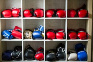 Various colourful boxing gloves stored on shelves in a boxing gymnasium.