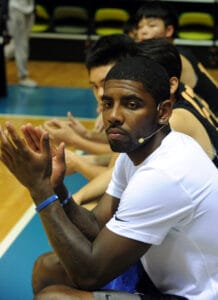 American basketball player Kyrie Irving, front, applauds as he watches Chinese fans playing basketball during an instructional activity in Hong Kong,