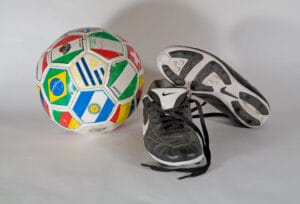 Old very used soccer football shoes and a soccer ball