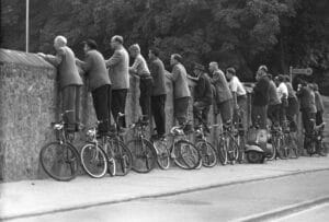 Men stand on their bicycles to look over a wall onto a soccer ground, photographed in September 1958 near Trier. Photo: Heinz-Jurgen Gottert +++(c) dpa - Report+++