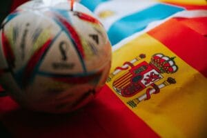 QATAR, DOHA, 18 JULY, 2022: Spain national Flag and Official Adidas World Cup Football Ball Al Rihla. And logo of FIFA World Cup in Qatar 2022